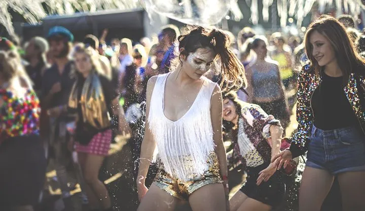 A woman dancing at an outdoor music festival at dusk