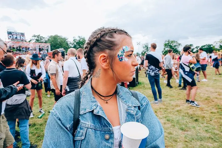 A young woman with face glitter at an outdoor music festival